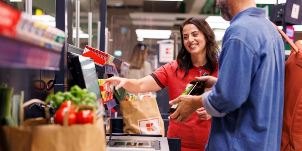 Kaufland-Verkaufsmitarbeiterin hilft einem Kunden an der SB-Kasse.